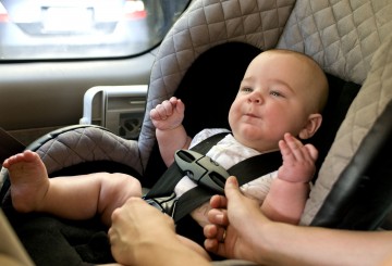 Baby in a back seat located child safety seat