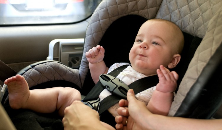 Baby in a back seat located child safety seat